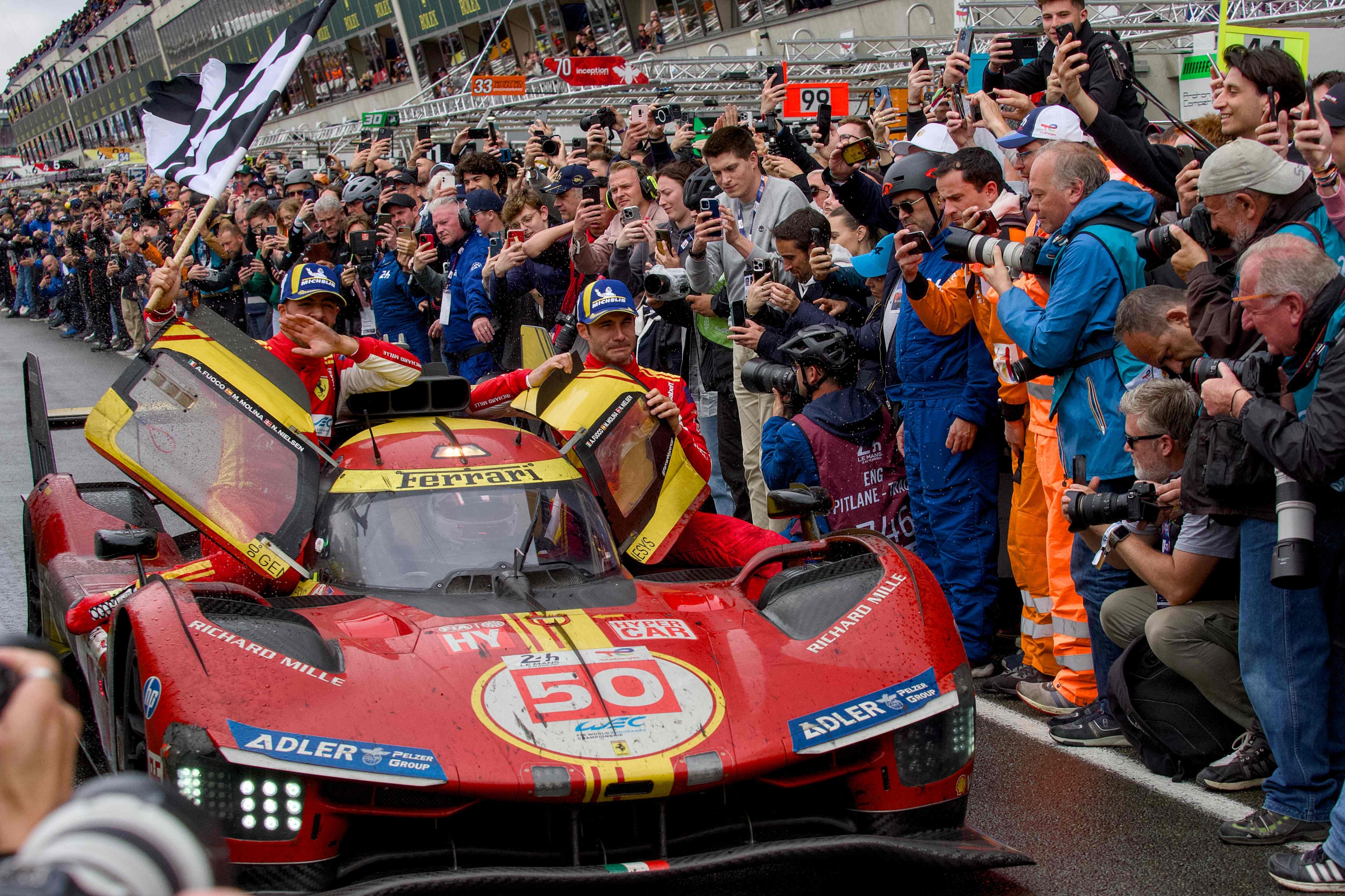 Ferrari 499P Hybrid Hypercar WEC's team, Spanish driver Miguel Molina (R) Italian driver Antonio Fuoco (L) and Danish driver Nicklas Nielsen (in the car) celebrate after winning Le Mans 24-hours endurance race in Le Mans, western France, on June 16, 2024. Ferrari won a wild and wet 92nd edition of the Le Mans 24 Hours race on June 16, 2024, as Nicklas Nielsen took the chequered flag after a vintage and gruelling race, the Dane sharing driving duties in the Italian constructor's No 50 car with Italian Antonio Fuoco and Spaniard Miguel Molina. (Photo by GUILLAUME SOUVANT / AFP)