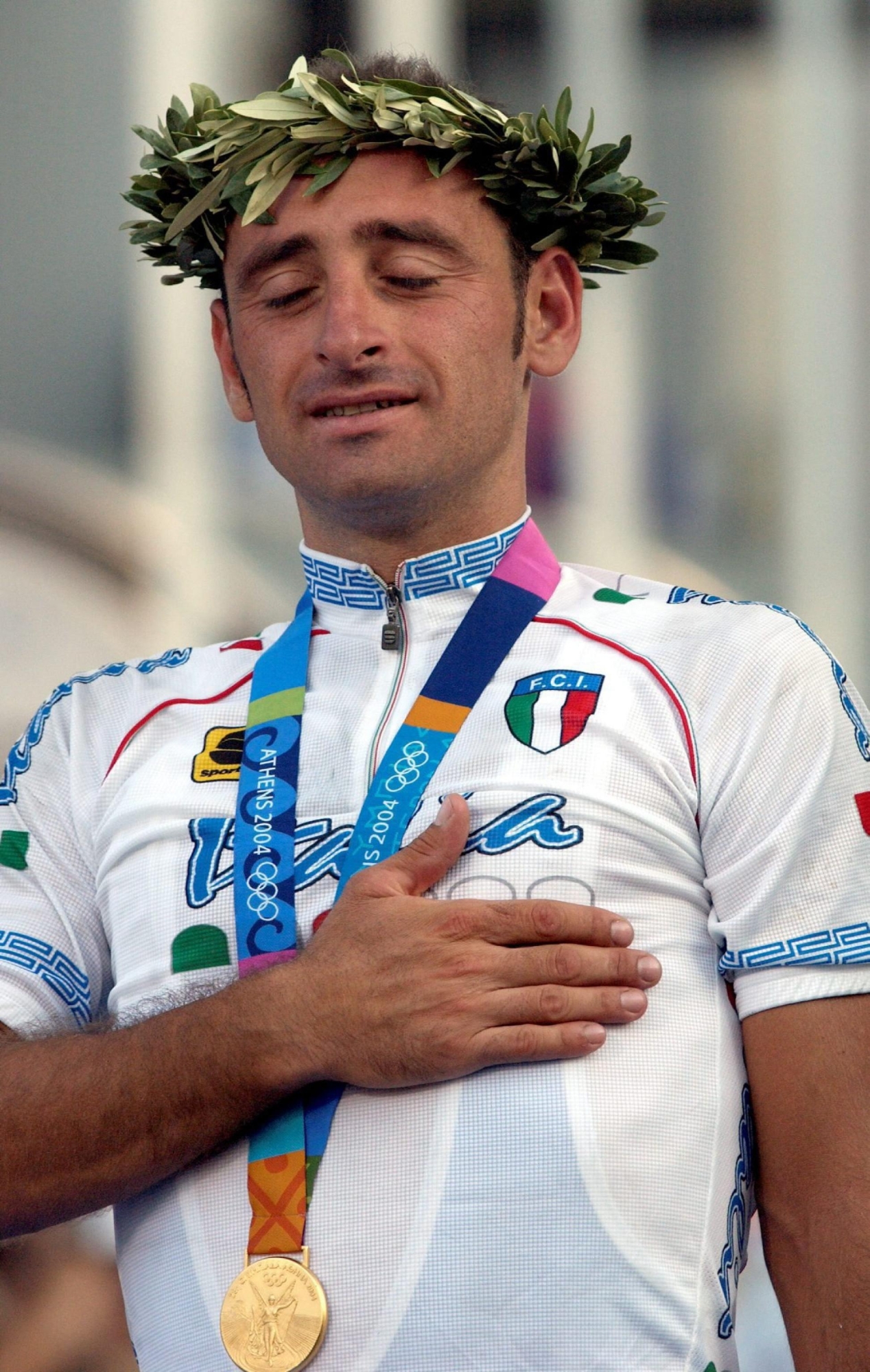 ATENE 2004:BETTINI;IL SALTO DEL 'GRILLO',DA GREGARIO ALL'ORO. Paolo Bettini from Italy reacts during the medal ceremony after winning the Olympic Street Race of Athens, Saturday 14 August 2004.  Bettini won gold, Portugal`s Sergio Paulinho  silver,  Axel Merckx from Belgium won bronze. ANSA - Peer Grimm - KRZ