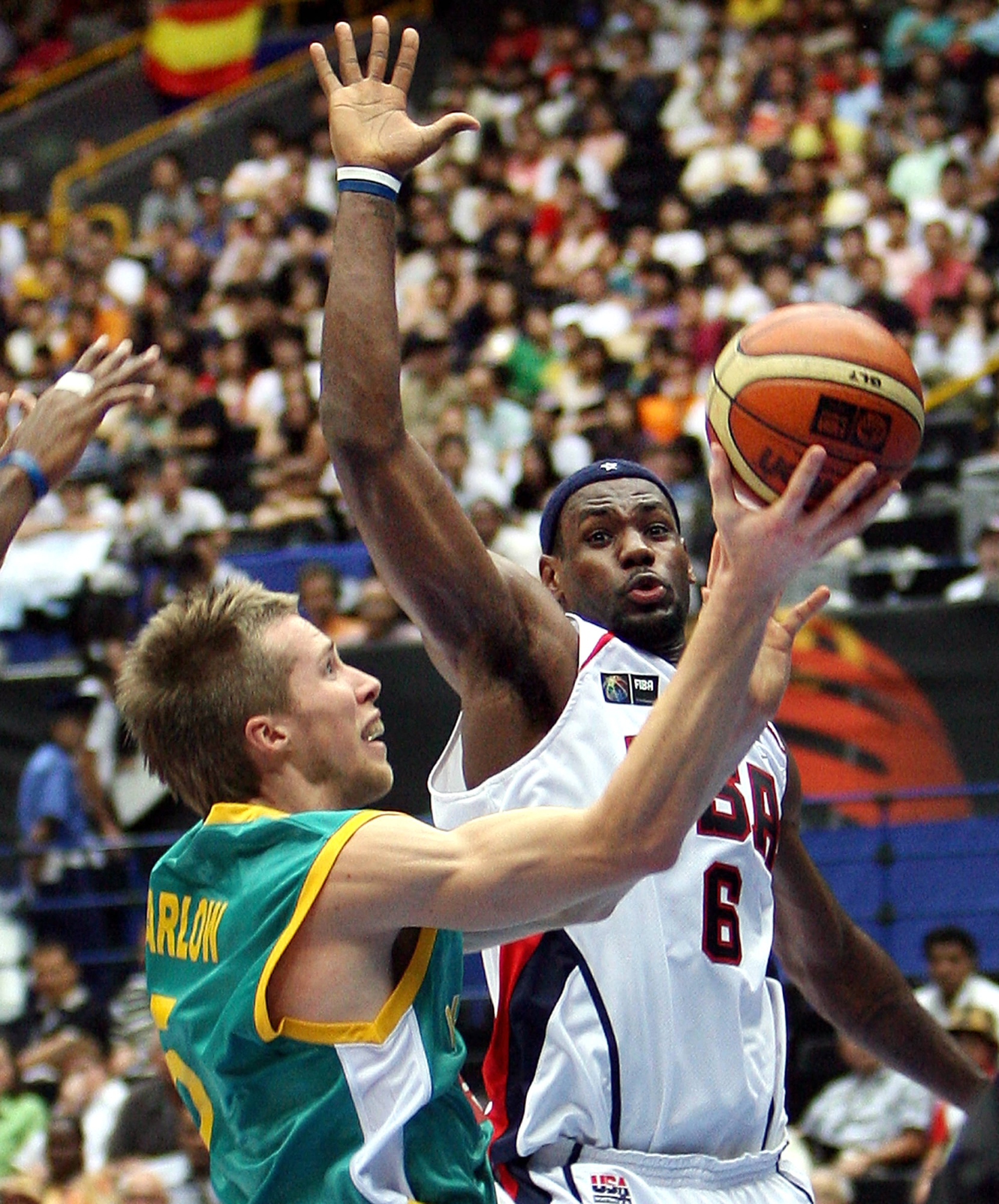 Australia's David Barlow (L) carries the ball under the net while LeBron James of the US (R) extends his hand during the eighth final of the World Basketball Championship in Saitama, suburban Tokyo 27 August 2006.  The US leads Australia 59-29 after the first half.    AFP PHOTO / YOSHIKAZU TSUNO (Photo by AFP)
