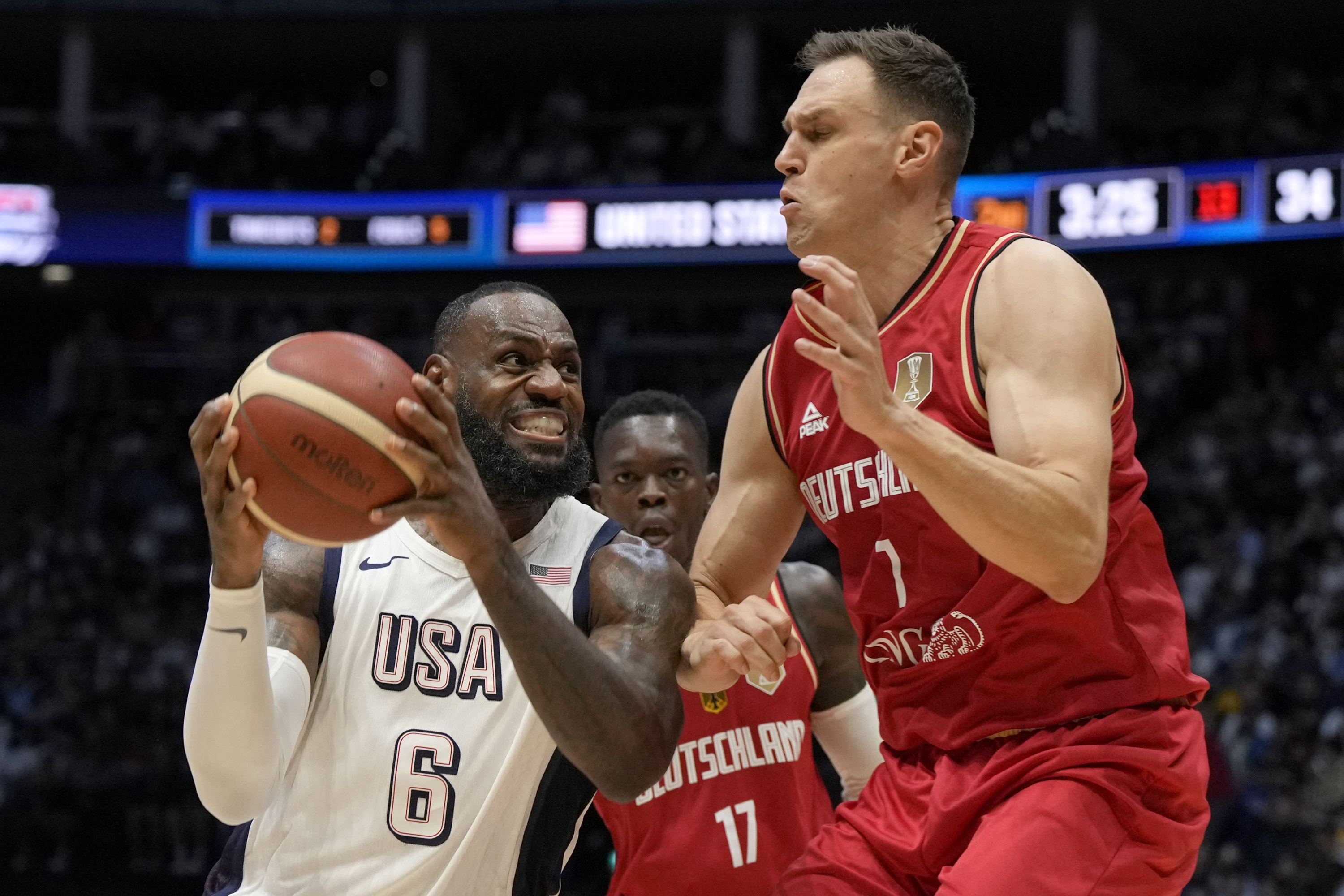 Germany's Johannes Voigtmann, right, blocks United States' forward LeBron James during an exhibition basketball game between the United States and Germany at the O2 Arena in London, Monday, July 22, 2024. (AP Photo/Alastair Grant)
