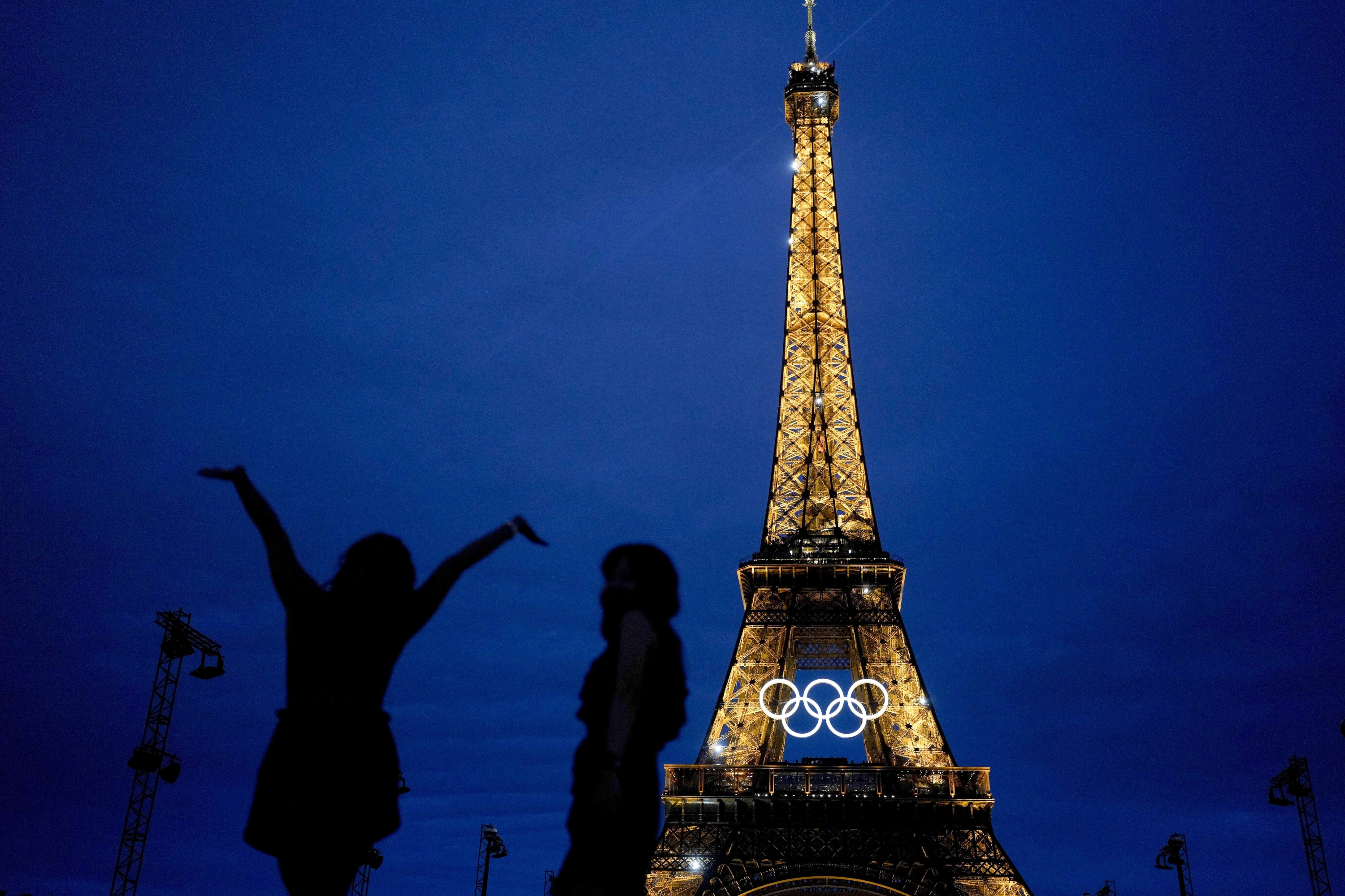 Team USA athletic trainer Amarilees Bolorin, left, poses for a selfie in front of the Eiffel Tower ahead of the 2024 Summer Olympics, in Paris, July 25, 2024. (AP Photo/Natacha Pisarenko)