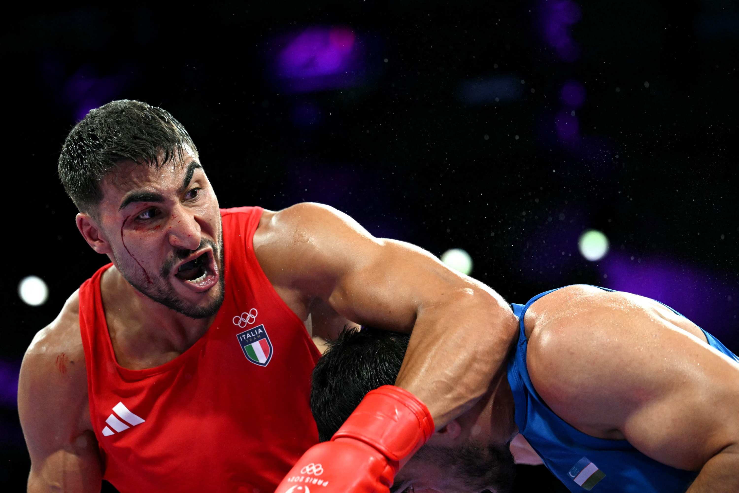 Italy's Aziz Abbes Mouhiidine (in red) fights against Uzbekistan's Lazizbek Mullojonov in the men's 92kg preliminaries round of 16 boxing match during the Paris 2024 Olympic Games at the North Paris Arena, in Villepinte on July 28, 2024. (Photo by MOHD RASFAN / AFP)