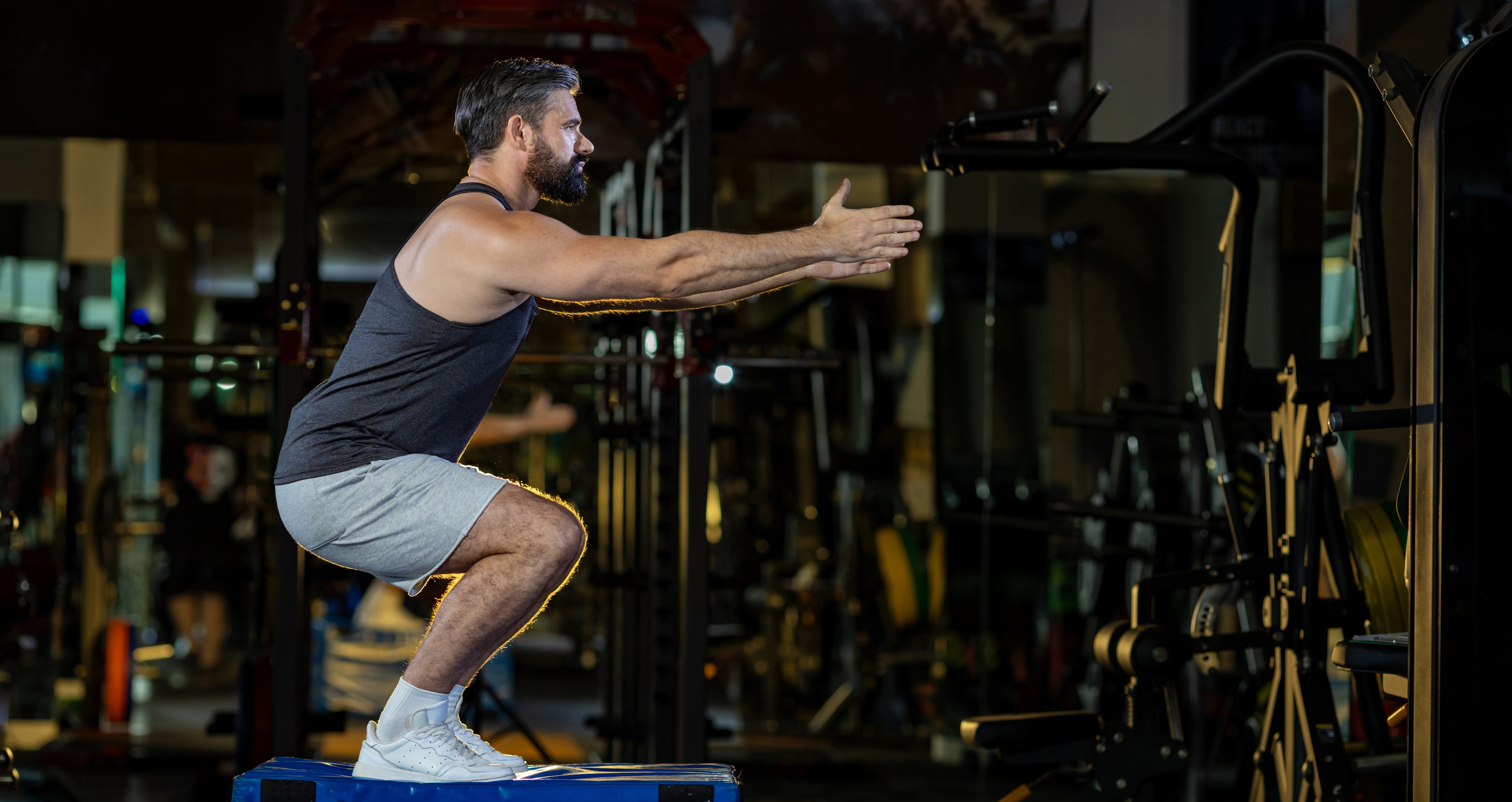 Caucasian man with strong and muscular firm shape is training on leg day by doing advance jump squat for thigh and calf muscle in gym for healthy and strong lower body weight strength