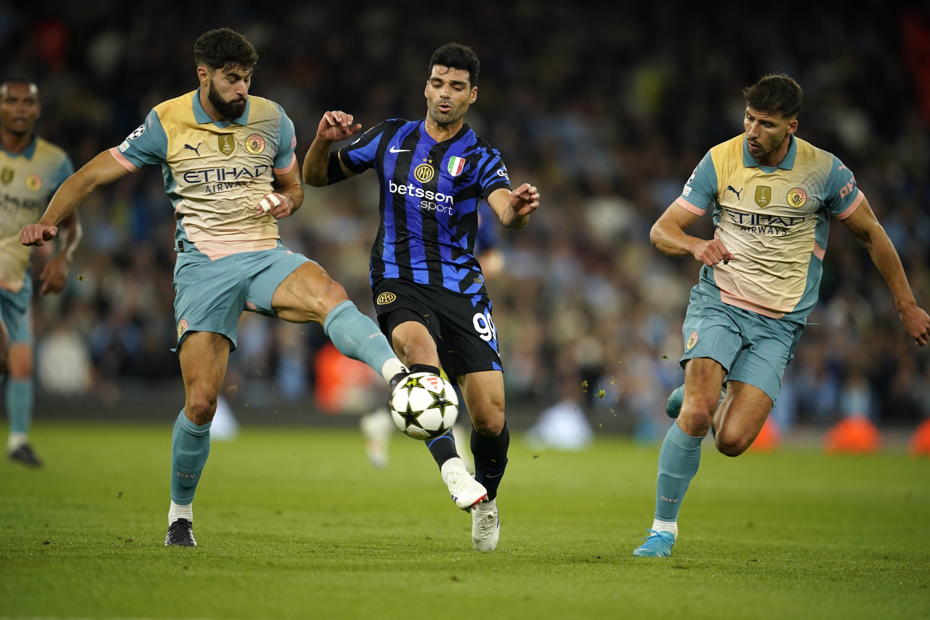 Inter Milan's Mehdi Taremi, center, fights for the ball with Manchester City's Josko Gvardiol, left, during the Champions League opening phase soccer match between Manchester City and Inter Milan at the Etihad Stadium, in Manchester, England, Wednesday, Sept. 18, 2024. (AP Photo/Dave Thompson)