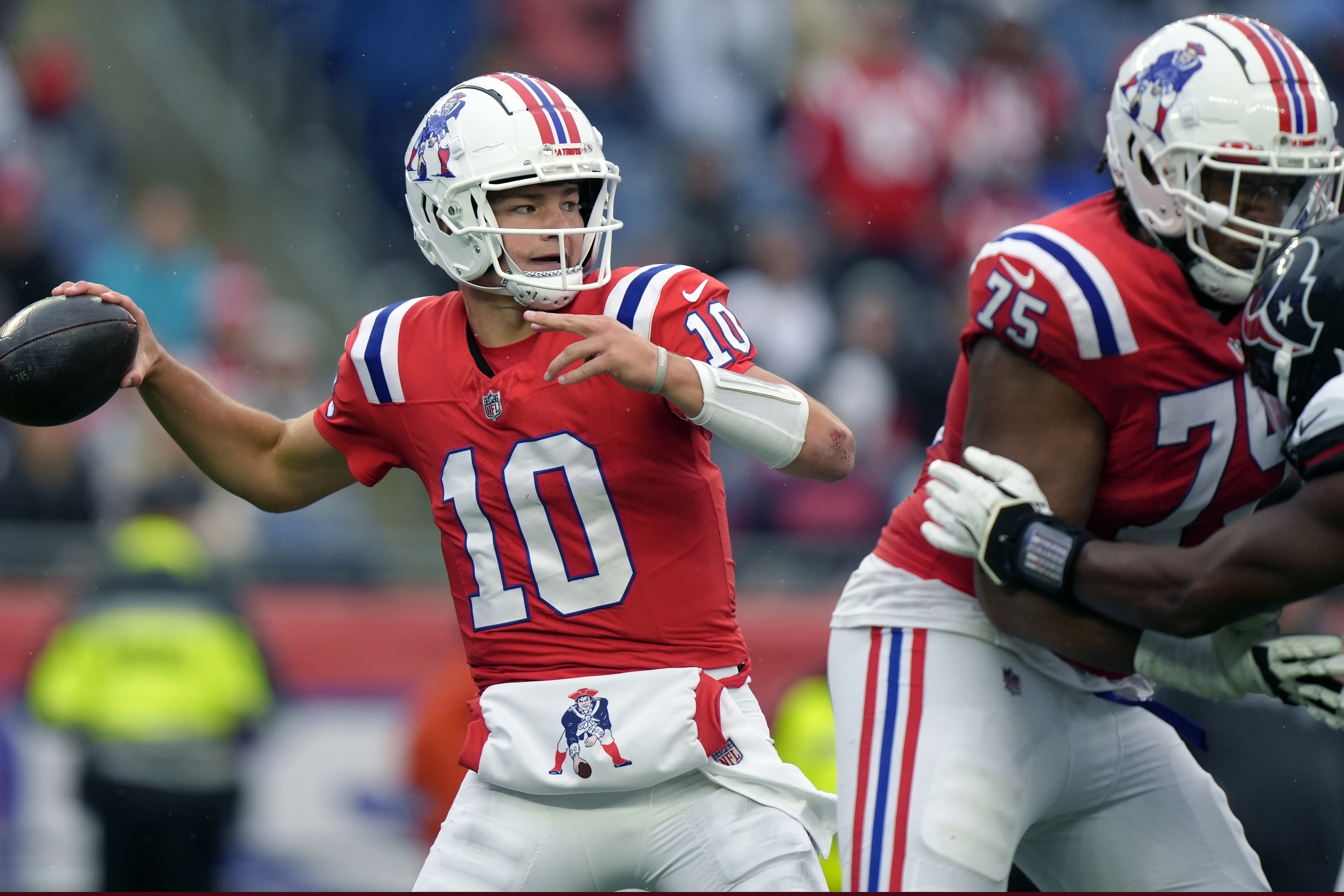 Il quarterback dei New England Patriots Drake Maye (10) cerca di passare la palla mentre il placcaggio offensivo Demontrey Jacobs (75) difende durante la seconda metà di una partita di football della NFL contro gli Houston Texans, domenica 13 ottobre 2024, a Foxborough, Massachusetts. (AP Photo/Steven Senne)