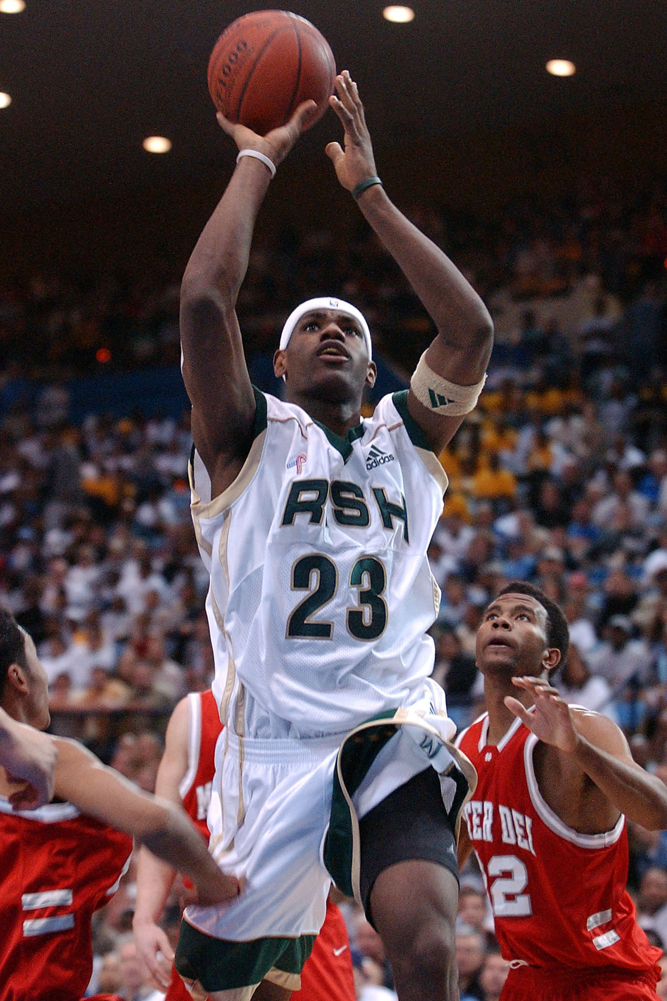 St. Vincent-St. Mary's LeBron James (C) goes up for a basket past Mater Dei's Wesley Washington (R), Chris Henry (back C) and Marcel Jones (L) in the first quarter, in Los Angeles, CA, 04 January 2003.  St. Vincent-St. Mary won 64-58 with James scoring 21 points.  James, 17, is expected to be the number one pick in the NBA draft this spring, following Kevin Garnett and Kobe Bryant in entering the NBA from high school.   AFP PHOTO/Lucy Nicholson (Photo by LUCY NICHOLSON / AFP)