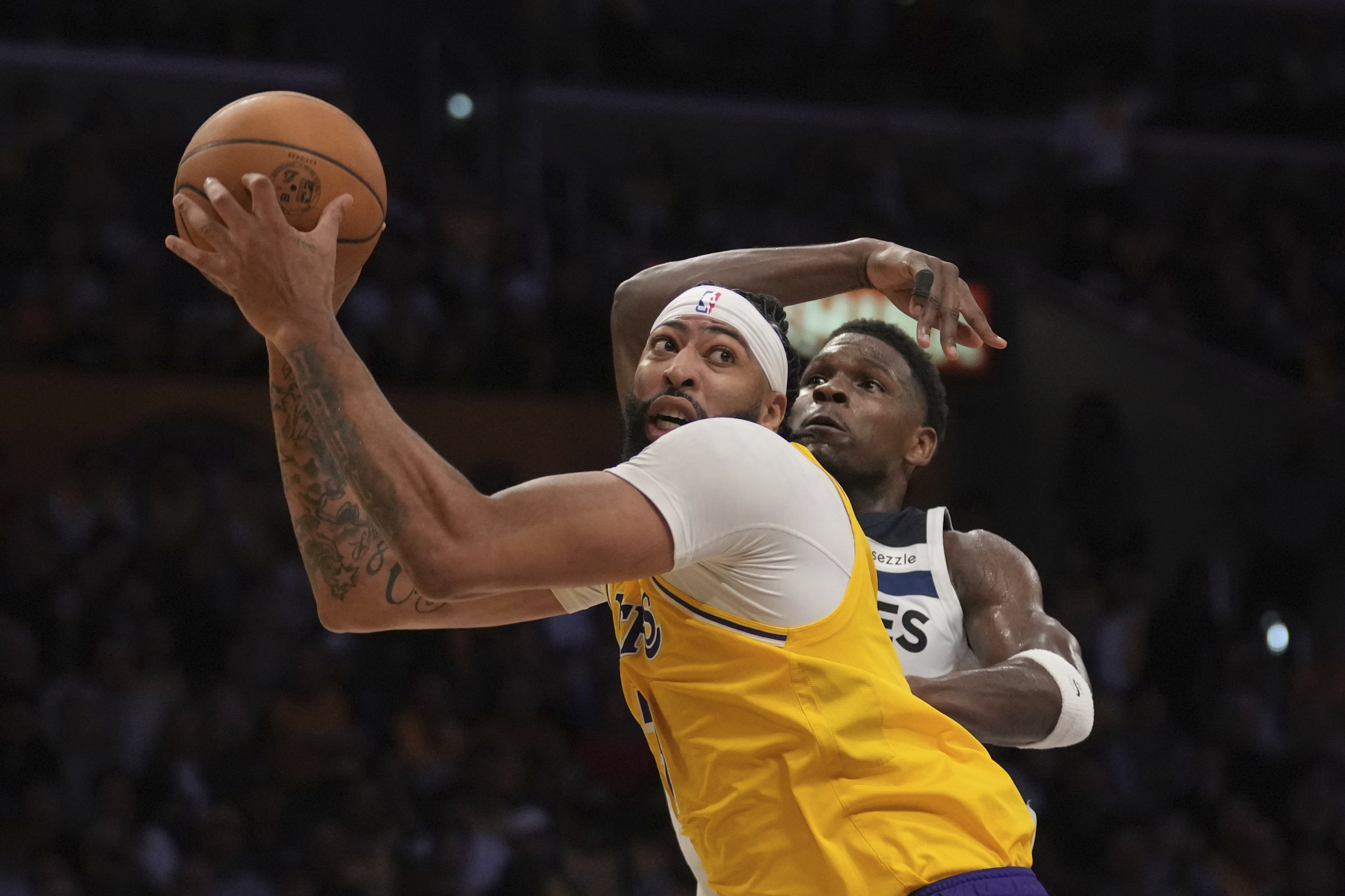 Los Angeles Lakers forward Anthony Davis, front, handles the ball as Minnesota Timberwolves guard Anthony Edwards defends during the second half of an NBA basketball game, Tuesday, Oct. 22, 2024, in Los Angeles. (AP Photo/Eric Thayer)