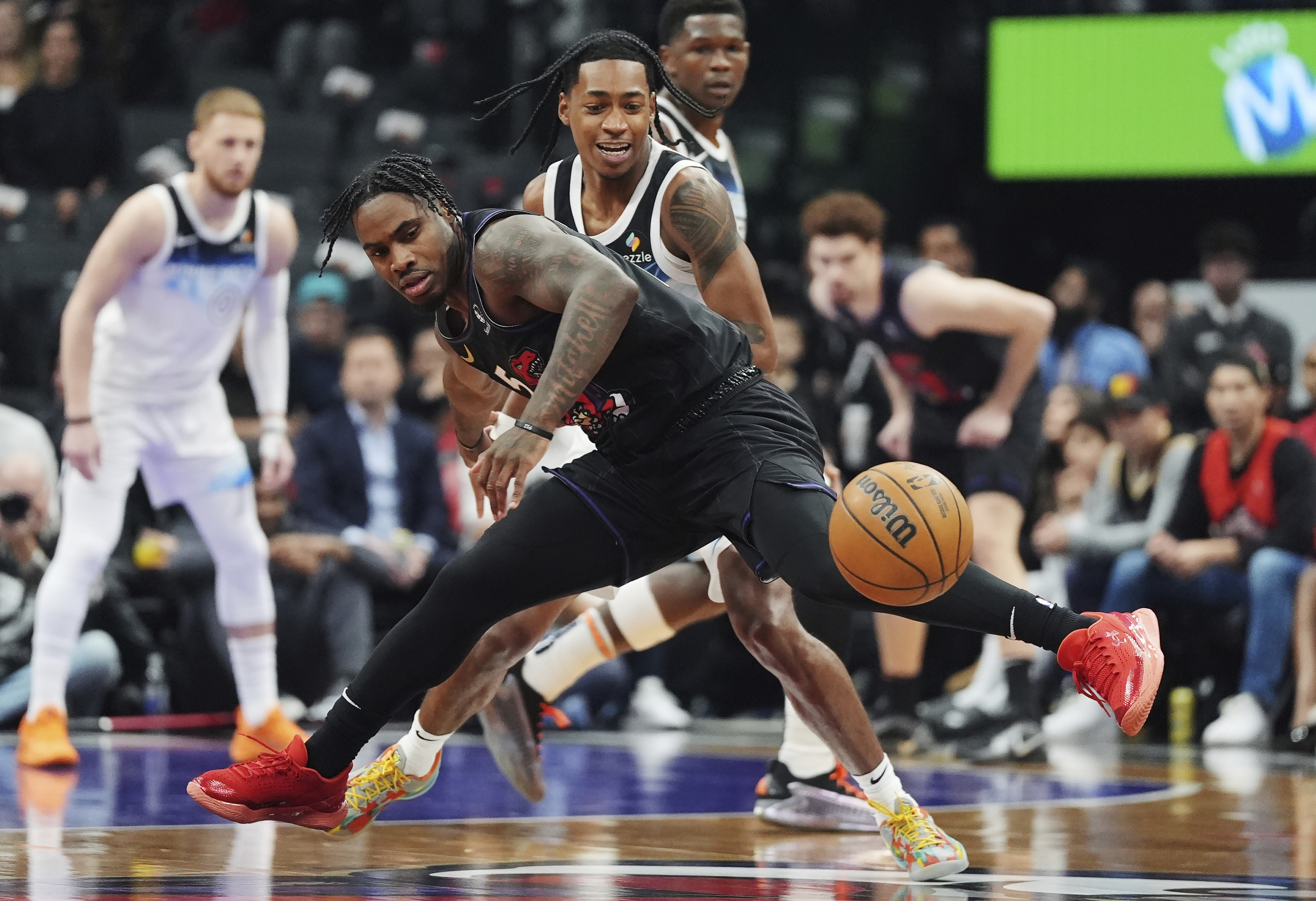 Toronto Raptors' Davion Mitchell (front) and Minnesota Timberwolves' Rob Dillingham (back) battle for the loose ball during first half NBA basketball action in Toronto on Thursday, Nov. 21, 2024. (Frank Gunn/The Canadian Press via AP)