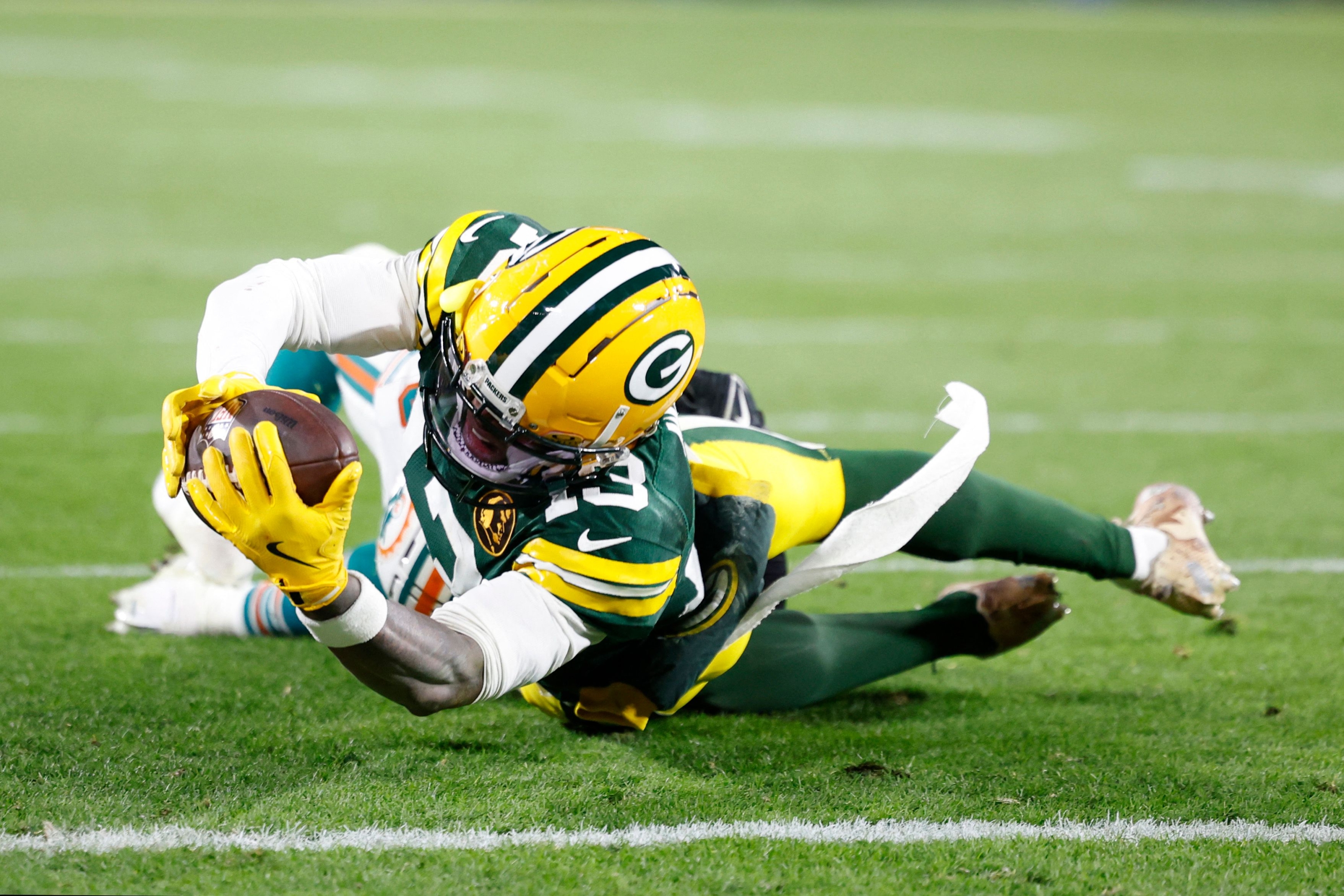 GREEN BAY, WISCONSIN - NOVEMBER 28: Dontayvion Wicks #13 of the Green Bay Packers reaches for the goal line during the second half of the game against the Miami Dolphins at Lambeau Field on November 28, 2024 in Green Bay, Wisconsin.   John Fisher/Getty Images/AFP (Photo by John Fisher / GETTY IMAGES NORTH AMERICA / Getty Images via AFP)