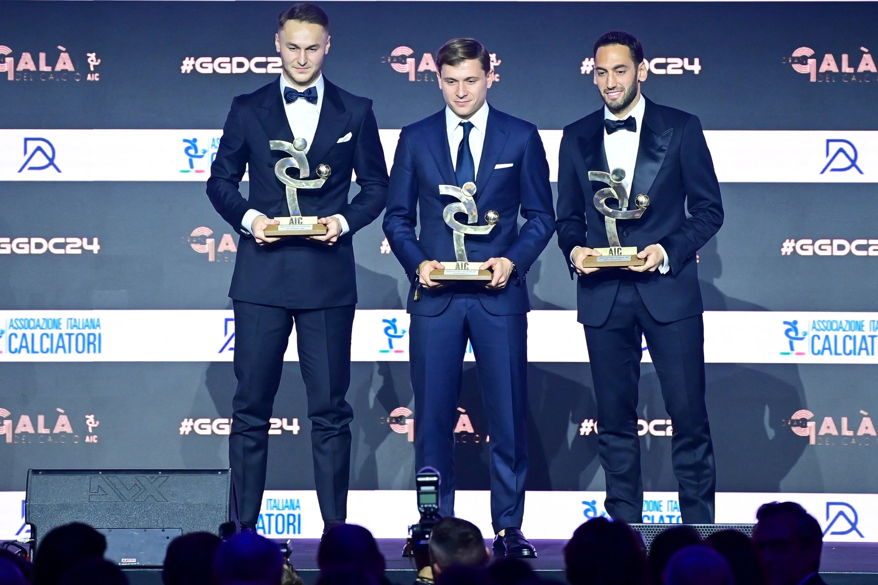 (L-R) Juventus' Dutch midfielder Teun Koopmeiners, Inter Milan's Italian midfielder Nicolo Barella and Inter Milan's Turkish midfielder Hakan Calhanoglu, pose on stage after receiving their Best Midfielder of the Year award during the Italian Footballers' Association (AIC) gala and awards ceremony in Milan, on December 2, 2024. (Photo by Piero CRUCIATTI / AFP)