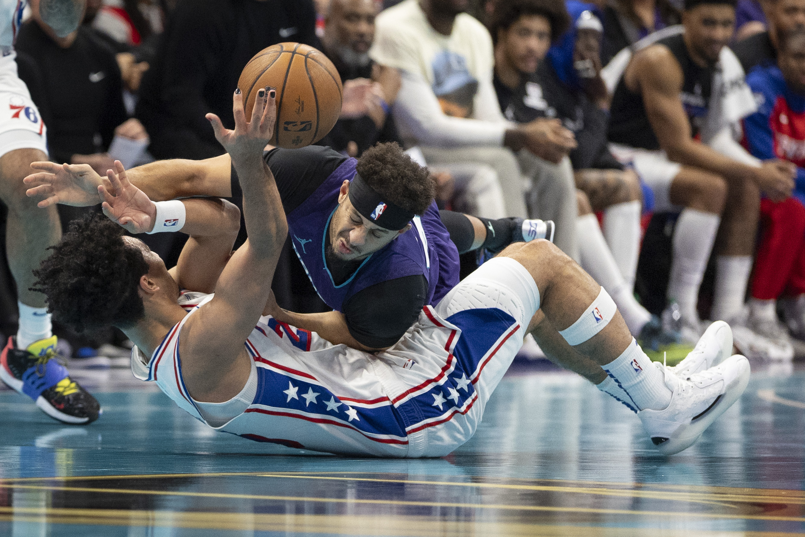 Charlotte Hornets guard Seth Curry, top, battles Philadelphia 76ers guard Jared McCain for a loose ball during the first half of an NBA Cup basketball game in Charlotte, N.C., Tuesday, Dec. 3, 2024. (AP Photo/Nell Redmond)