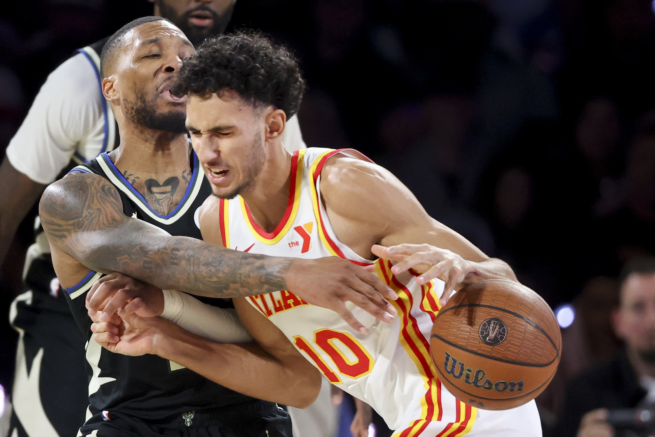 Milwaukee Bucks guard Damian Lillard, left, fouls Atlanta Hawks forward Zaccharie Risacher (10) during the second half of a semifinal game in the NBA Cup basketball tournament Saturday, Dec. 14, 2024, in Las Vegas. (AP Photo/Ian Maule)