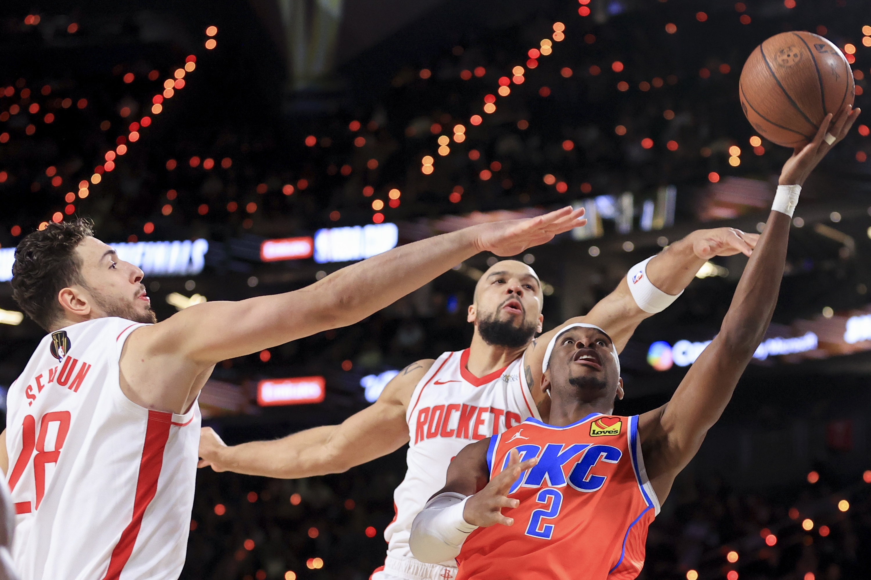 Oklahoma City Thunder guard Shai Gilgeous-Alexander (2) shoots against Houston Rockets center Alperen Sengun (28) and forward Dillon Brooks, back right, during the first half of a semifinal game in the NBA Cup basketball tournament Saturday, Dec. 14, 2024, in Las Vegas. (AP Photo/Ian Maule)