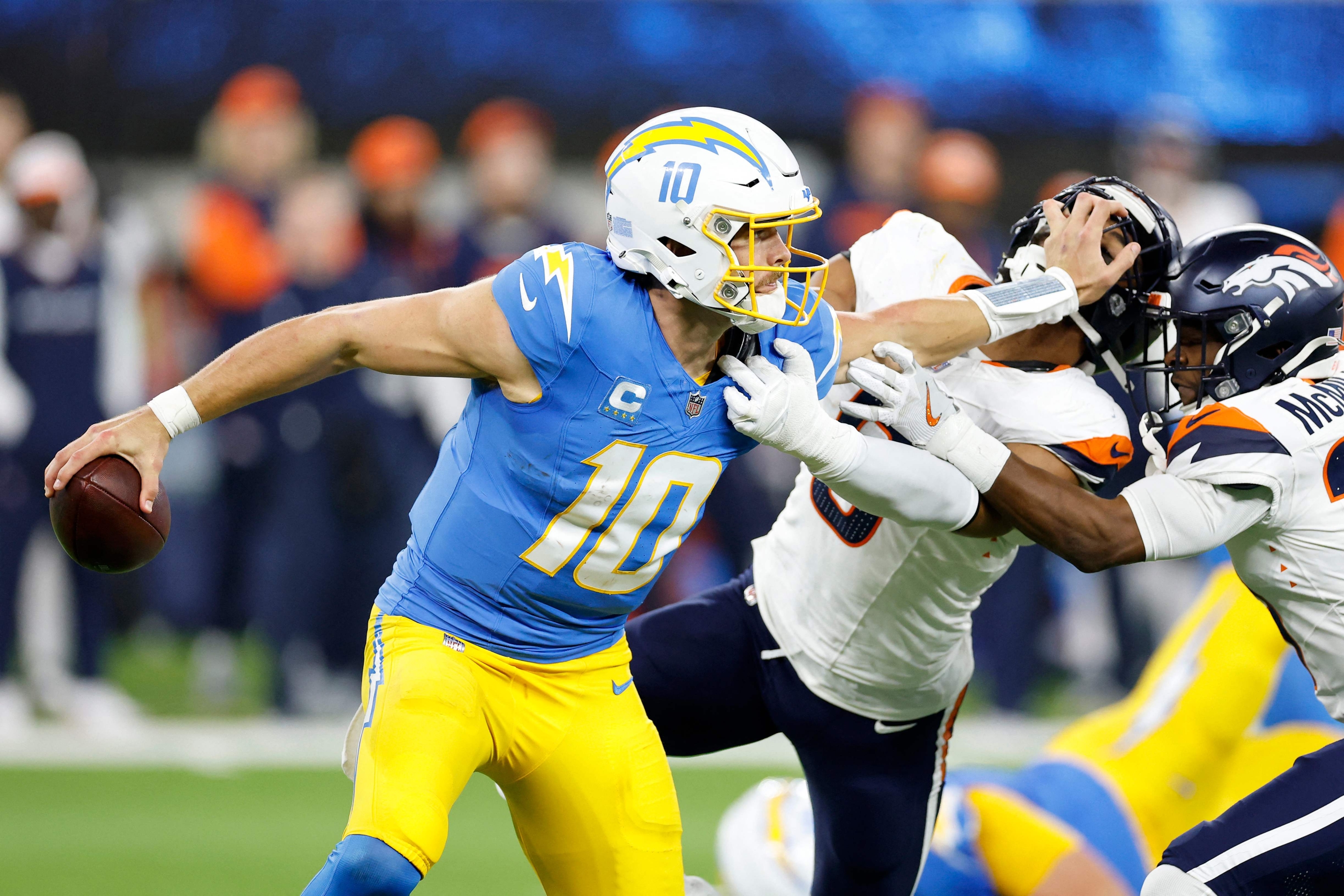 INGLEWOOD, CALIFORNIA - DECEMBER 19: Justin Herbert #10 of the Los Angeles Chargers stiff arms Jonathon Cooper #0 of the Denver Broncos during the fourth quarter in the game at SoFi Stadium on December 19, 2024 in Inglewood, California.   Ronald Martinez/Getty Images/AFP (Photo by RONALD MARTINEZ / GETTY IMAGES NORTH AMERICA / Getty Images via AFP)