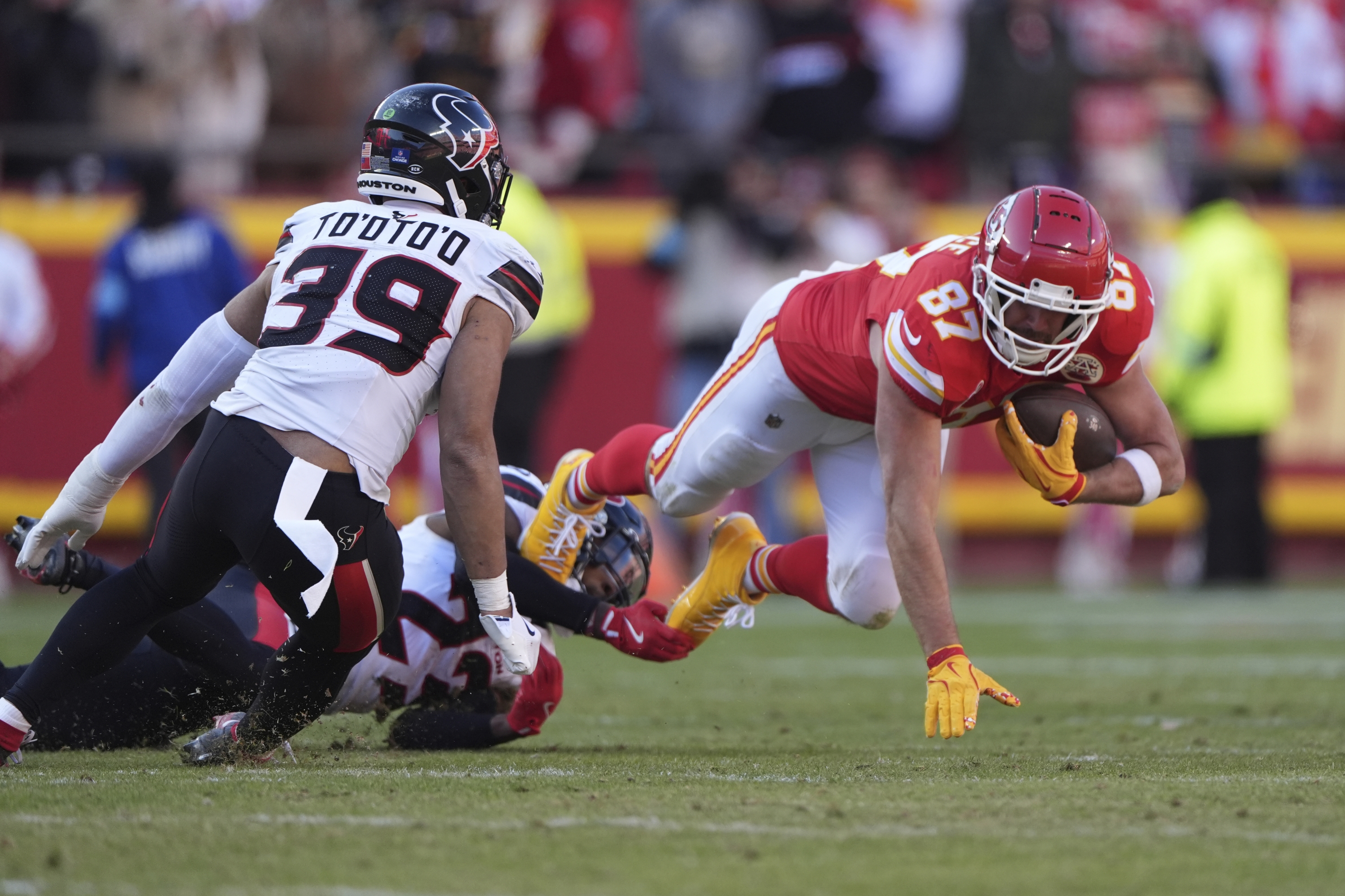 Kansas City Chiefs tight end Travis Kelce (87) gains a first down as he is stopped by Houston Texans safety Eric Murray (23) and linebacker Henry To'oTo'o (39) during the second half of an NFL football game Saturday, Dec. 21, 2024, in Kansas City, Mo. (AP Photo/Charlie Riedel)