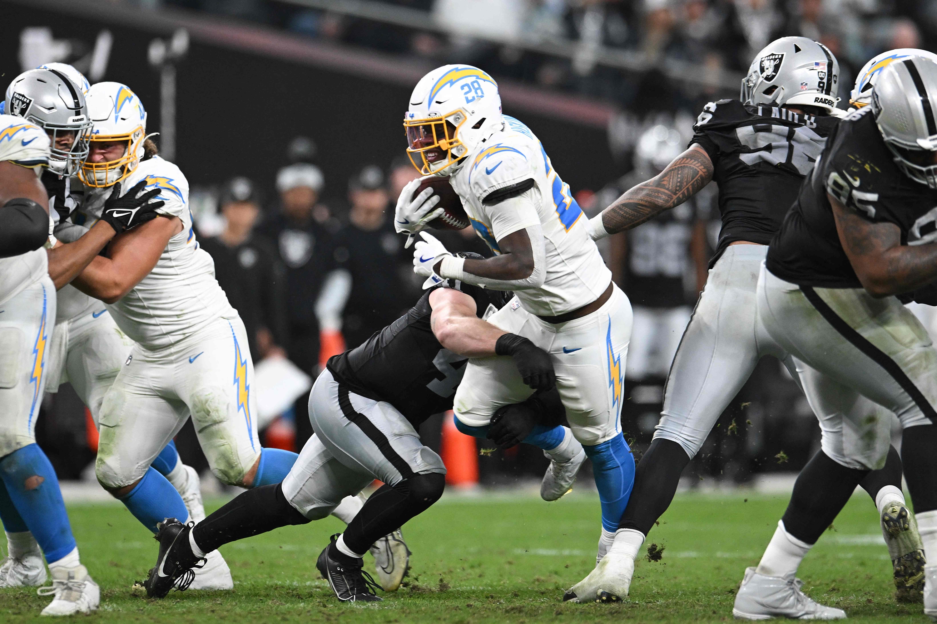 LAS VEGAS, NEVADA - JANUARY 05: Robert Spillane #41 of the Las Vegas Raiders tackles Hassan Haskins #28 of the Los Angeles Chargers during the fourth quarter at Allegiant Stadium on January 05, 2025 in Las Vegas, Nevada.   Candice Ward/Getty Images/AFP (Photo by Candice Ward / GETTY IMAGES NORTH AMERICA / Getty Images via AFP)