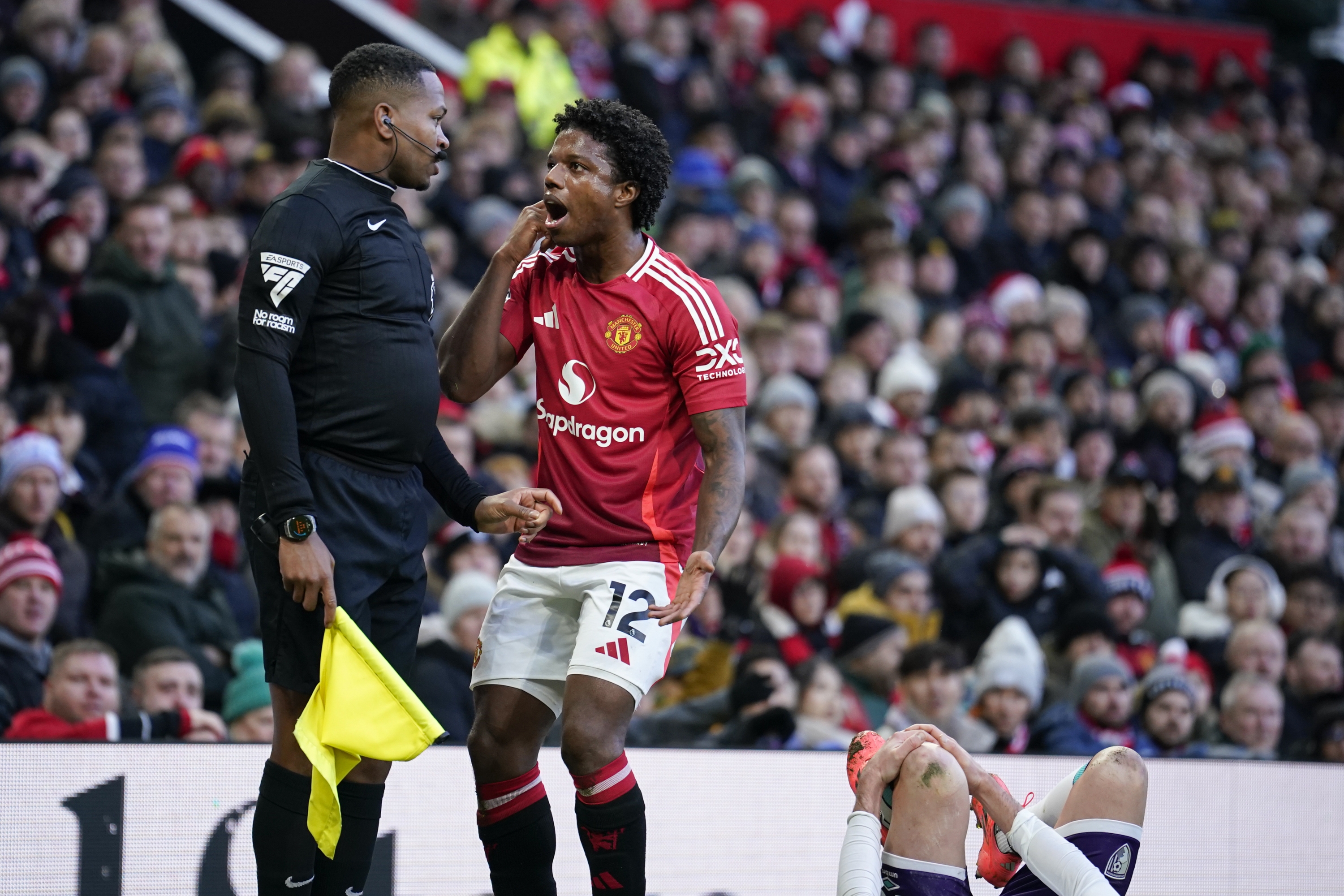 Manchester United's Tyrell Malacia argues with line referee Akil Howson after a foul on Bournemouth's Adam Smith, bottom right, during the English Premier League soccer match between Manchester United and Bournemouth at the Old Trafford stadium in Manchester, England, Sunday, Dec. 22, 2024. (AP Photo/Dave Thompson)