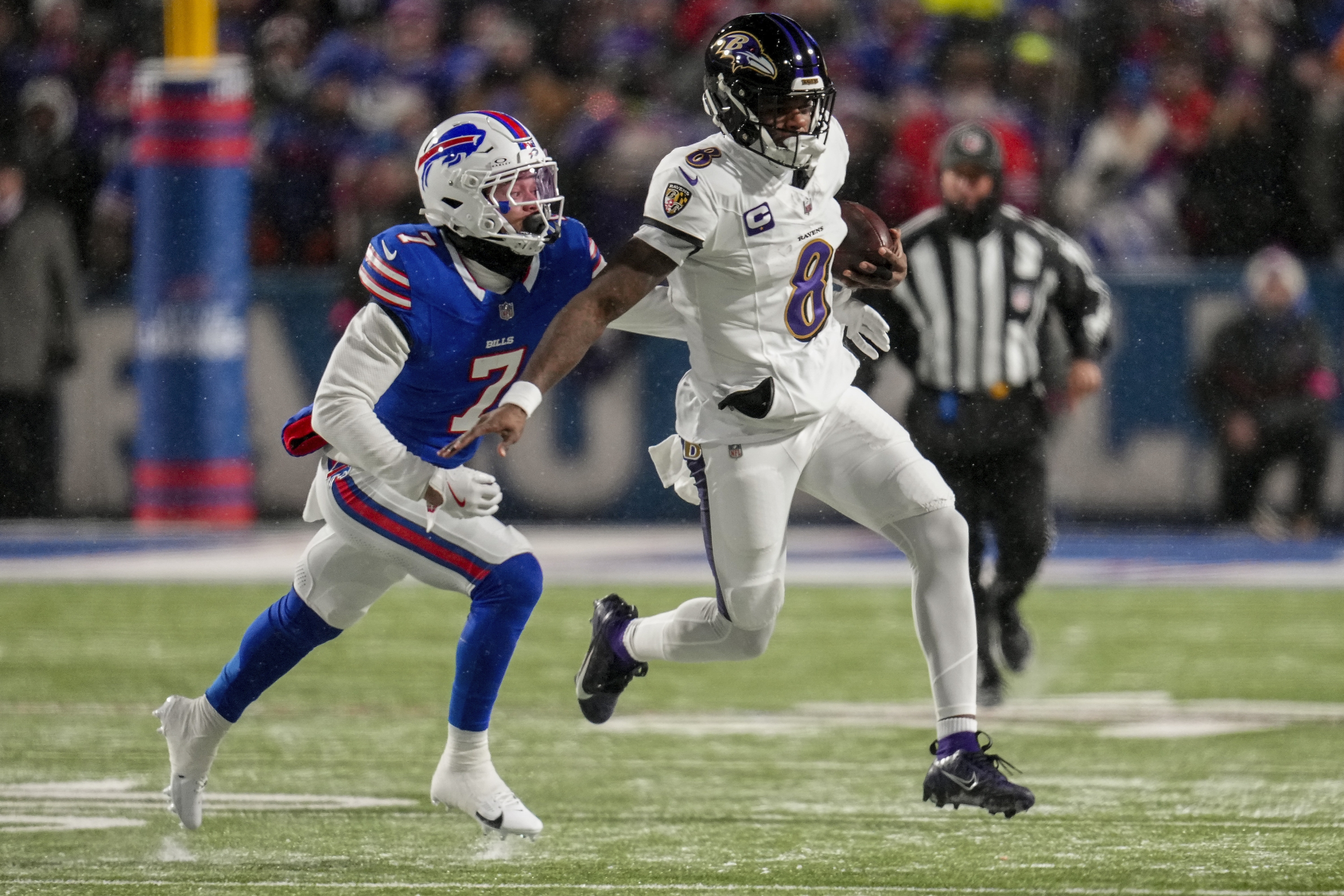 Baltimore Ravens quarterback Lamar Jackson (8) carries the ball for a first down against Buffalo Bills cornerback Taron Johnson (7) during the first quarter of an NFL divisional playoff football game, Sunday, Jan. 19, 2025, in Orchard Park, N.Y. (AP Photo/Gene J. Puskar)