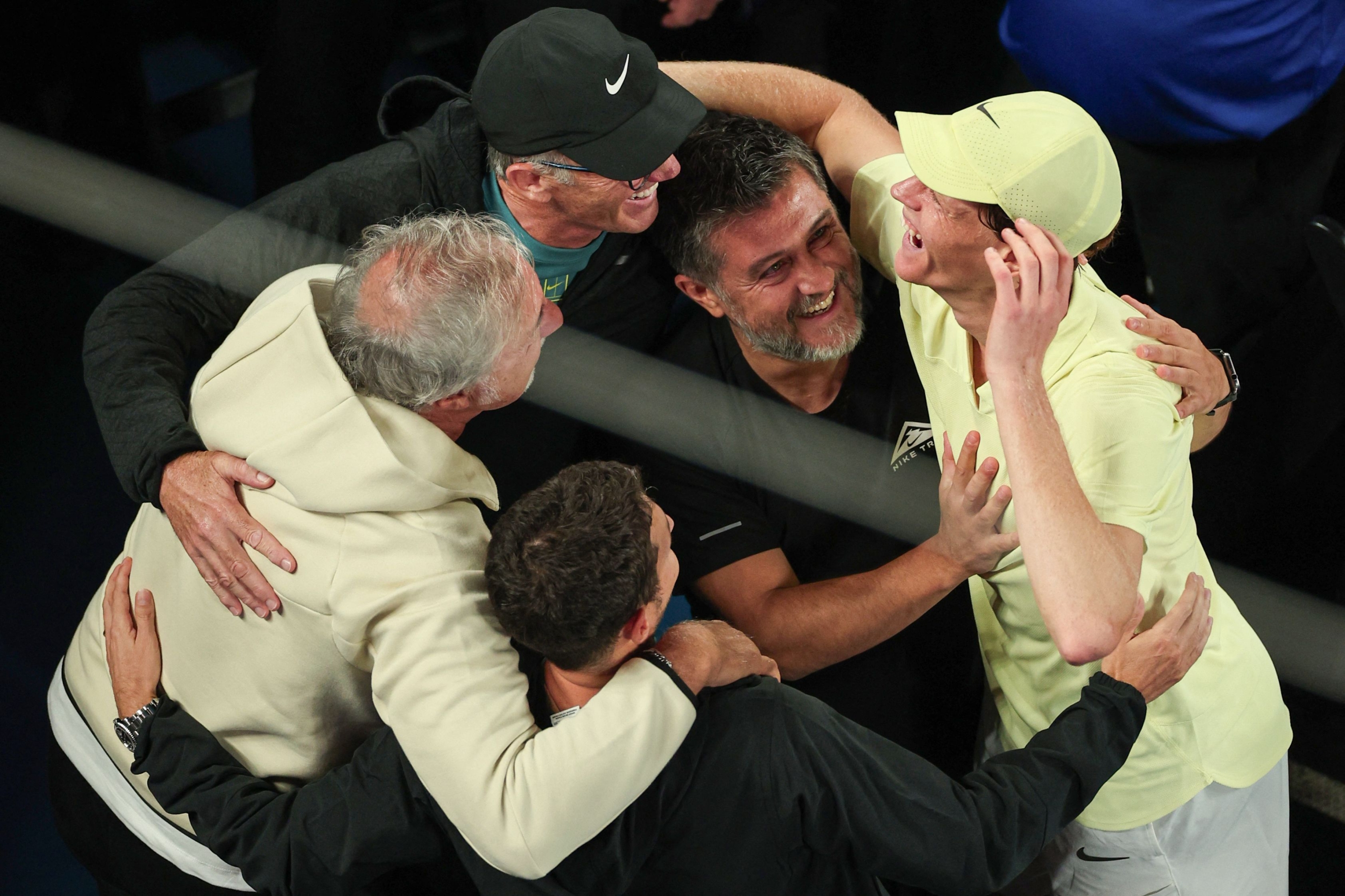 TOPSHOT - Italy's Jannik Sinner (R) celebrates with his team after his victory against Germany's Alexander Zverev during their men's singles final match on day fifteen of the Australian Open tennis tournament in Melbourne on January 26, 2025. (Photo by Adrian Dennis / AFP) / -- IMAGE RESTRICTED TO EDITORIAL USE - STRICTLY NO COMMERCIAL USE --