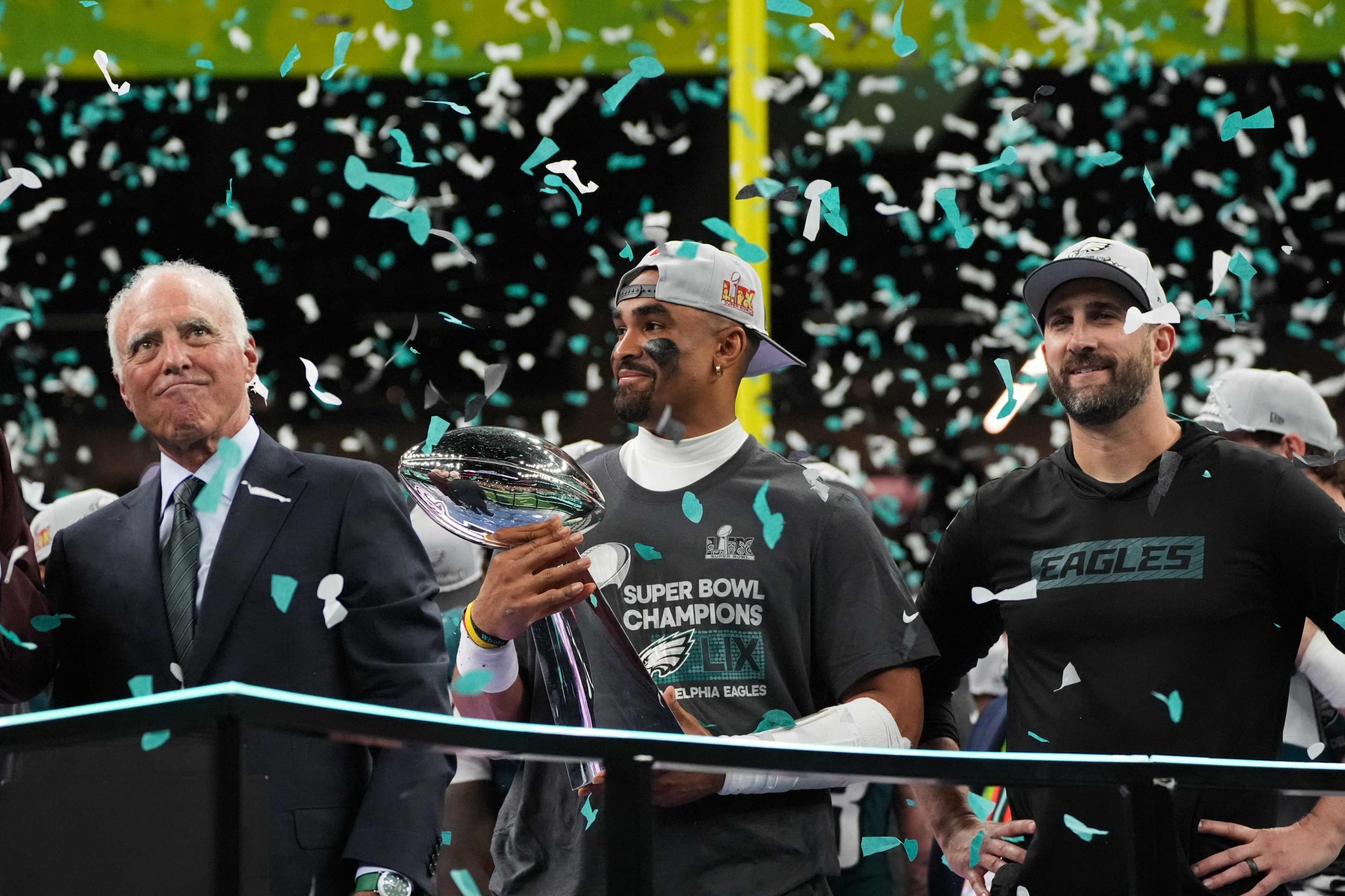 (L-R) Philadelphia Eagles owner, chairman and CEO Jeffrey Lurie, Philadelphia Eagles' quarterback #01 Jalen Hurts and Philadelphia Eagles' head coach Nick Sirianni celebrate with the Vince Lombardi Trophy at the end of Super Bowl LIX, after the Philadelphia Eagles defeated the Kansas City Chiefs 40-22 at Caesars Superdome in New Orleans, Louisiana, February 9, 2025. (Photo by TIMOTHY A. CLARY / AFP)