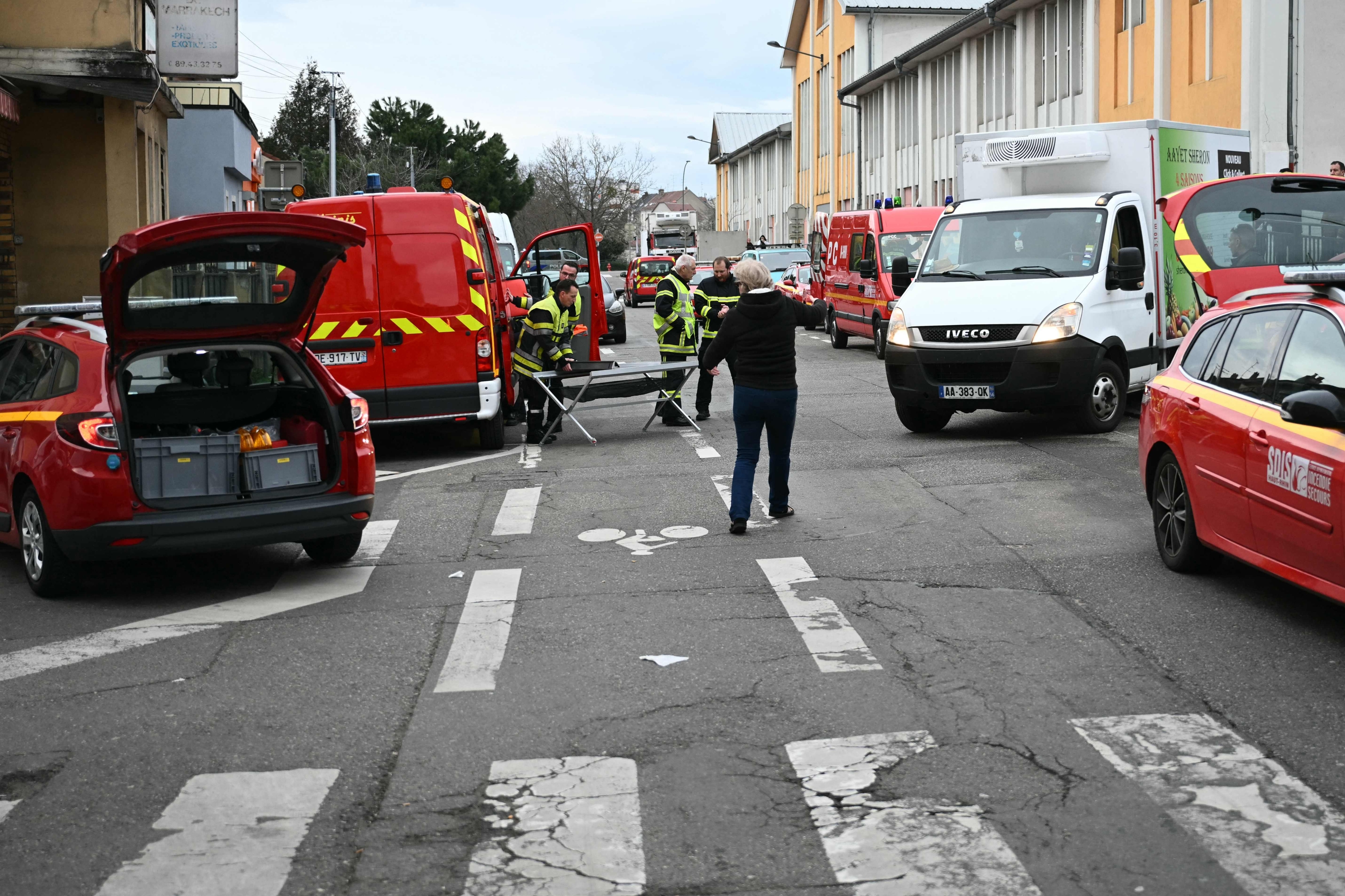 French firefighters (C) operate near the site of a bladed weapon attack where a man is suspected of killing one person and wounding two municipal police officers in Mulhouse, eastern France on February 22, 2025. (Photo by SEBASTIEN BOZON / AFP)