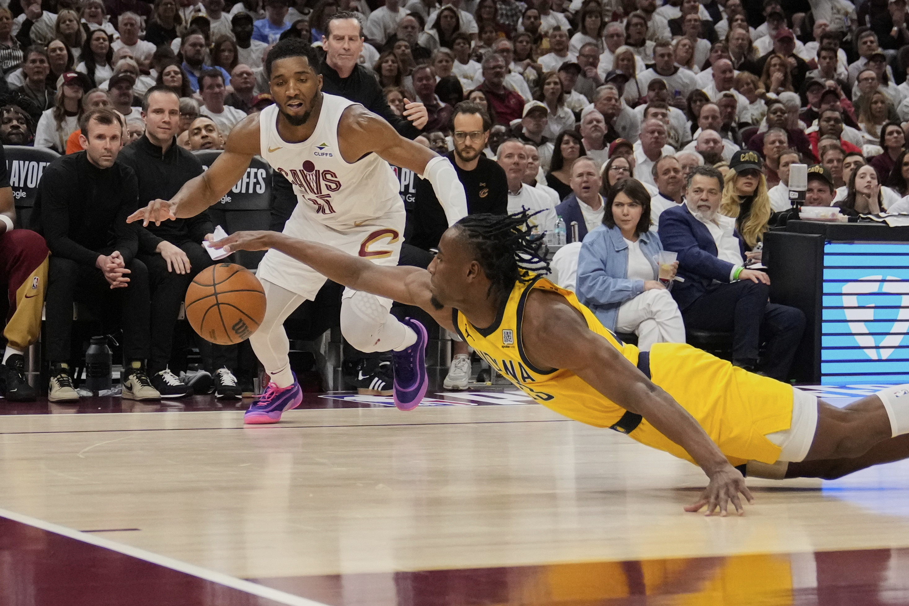 Indiana Pacers forward Aaron Nesmith, right, dives for a ball in front of Cleveland Cavaliers guard Donovan Mitchell (45) in the second half during Game 2 in the Eastern Conference semifinals of the NBA basketball playoffs Tuesday, May 6, 2025, in Cleveland. (AP Photo/Sue Ogrocki)