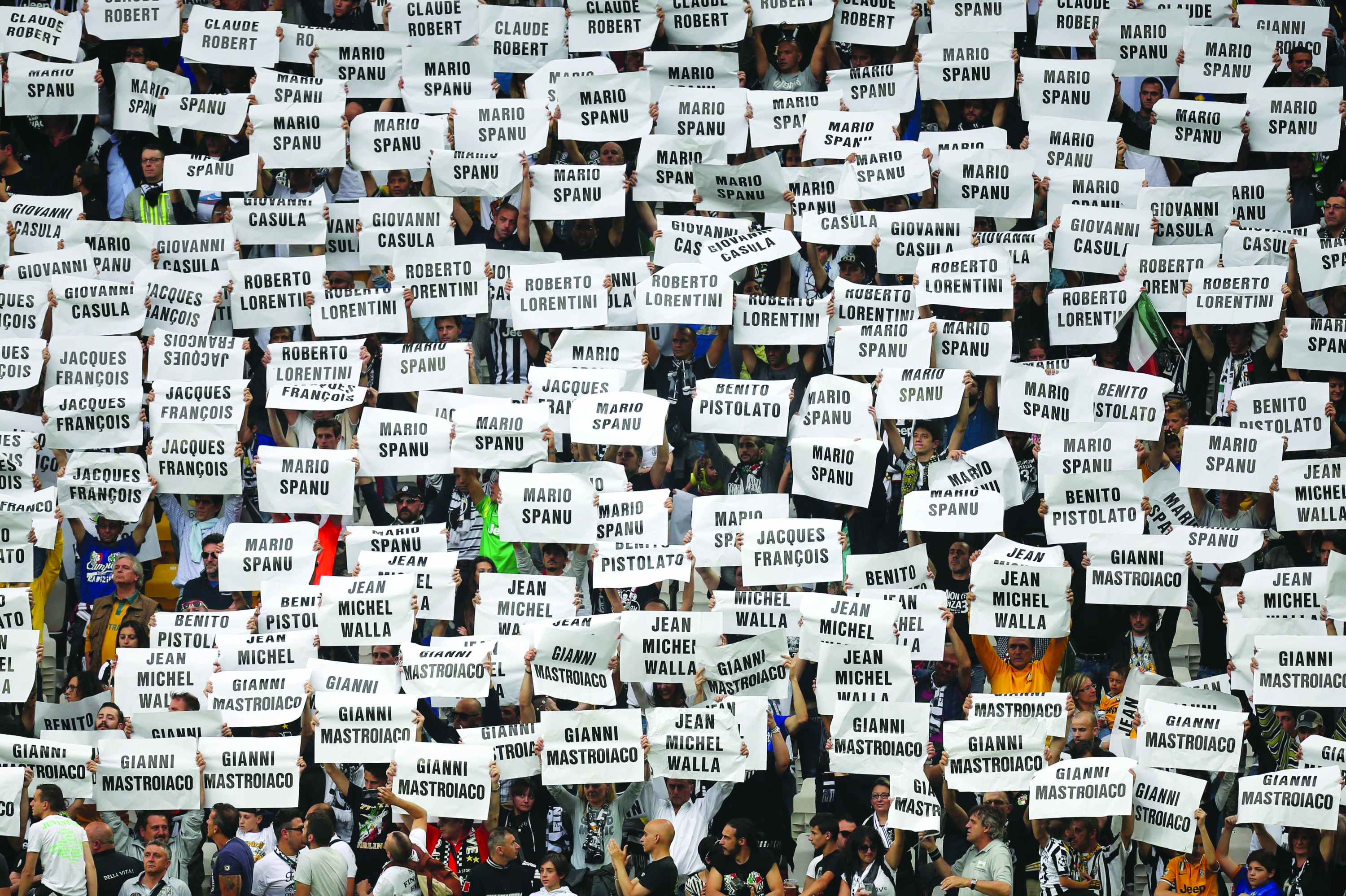 Juventus fans hold posters with the names of the victims of the Heysel stadium tragegy, during the Italian Serie A football match Juventus vs Napoli on May 23, 2015 at the Juventus stadium in Turin. The tragedy occured when a wall collapsed in the stadium under the pressure of people and crushed Juventus fans as they tried to escape Liverpool supporters during the European Cup Final between Juventus and Liverpool killing 39 people on May 29, 1985 in Brussels. AFP PHOTO / MARCO BERTORELLO (Photo by MARCO BERTORELLO / AFP)