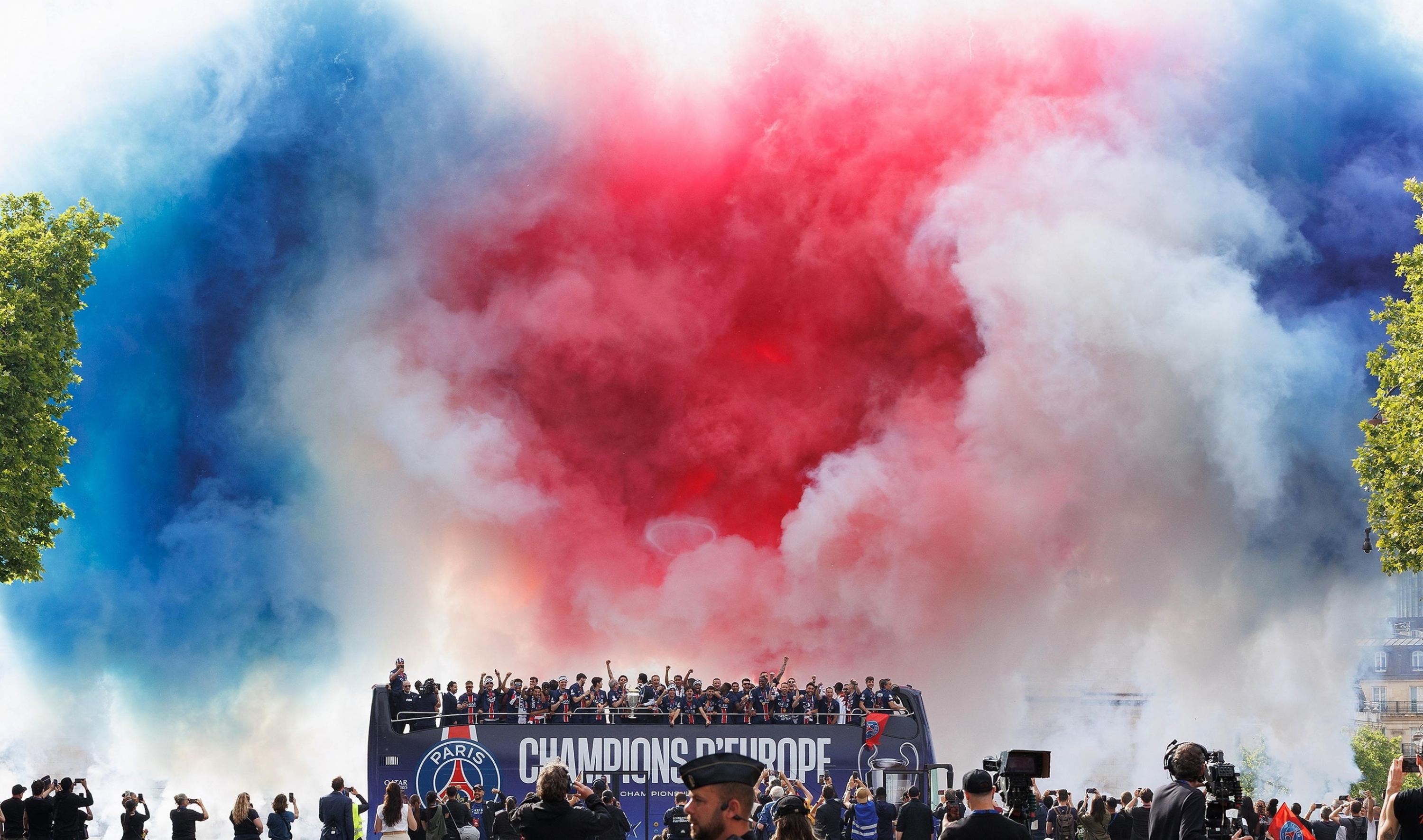 epa12149564 PSG team and staff celebrate under smoke coloured in the French national colours during an open-top bus parade of the team on the Champs Elysee boulevard in Paris, France, 01 June 2025. Paris Saint-Germain won the UEFA Champions League for the first time in the club's history after beating Internazionale Milano on 31 May 2025 in the final in Munich. EPA/SADAK SOUICI