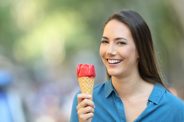 Happy woman holding an ice cream looking at you