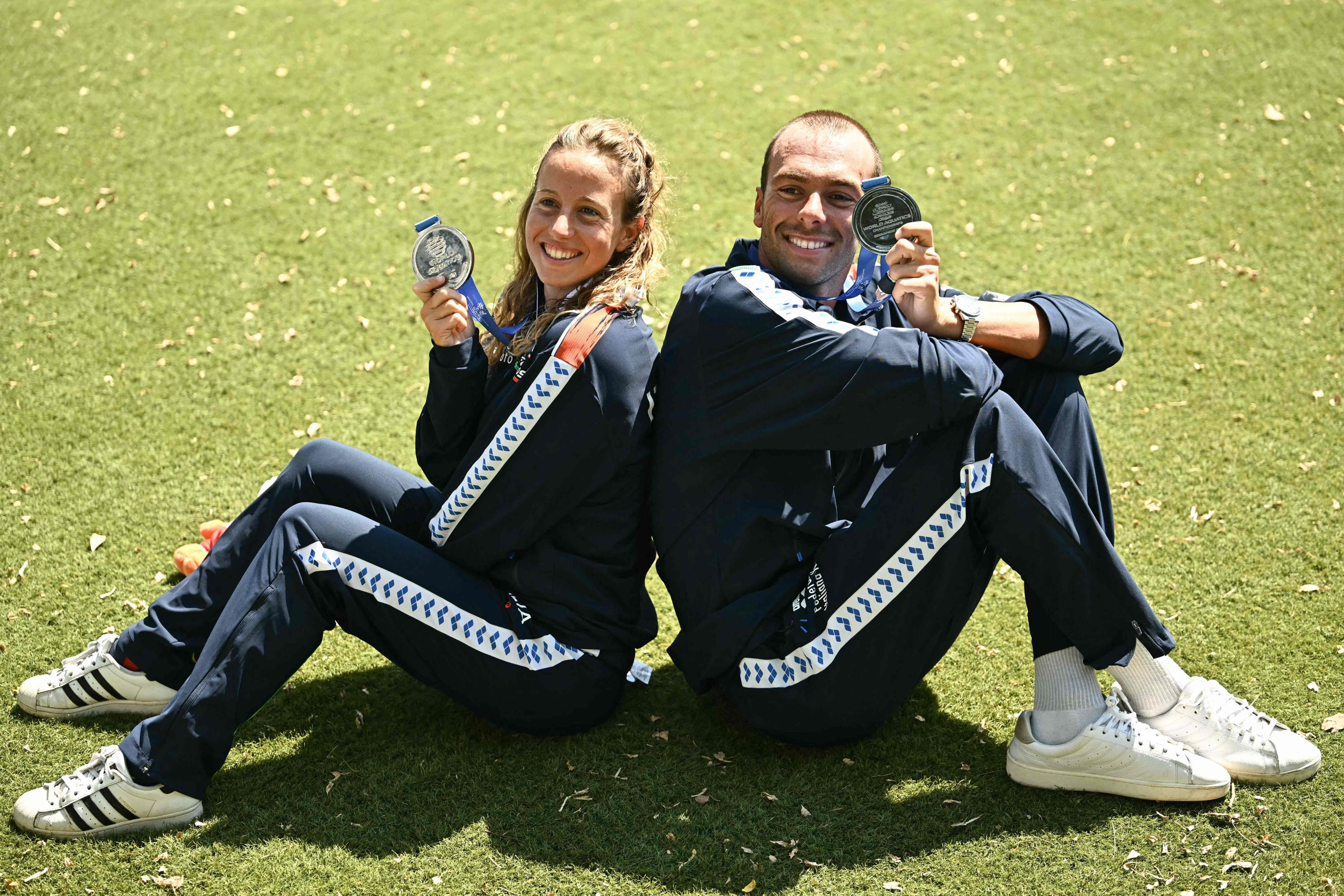 O nadador italiano Gregorio Paltrinieri (D), segundo colocado na prova de natação em águas abertas masculina de 5 km, e a nadadora italiana Ginevra Taddeucci, segunda colocada na prova de natação em águas abertas feminina de 5 km, comemoram com suas medalhas de prata após suas provas durante o Campeonato Mundial de Esportes Aquáticos de 2025 na Ilha de Sentosa, em Cingapura, em 18 de julho de 2025. (Foto de Manan VATSYAYANA / AFP)