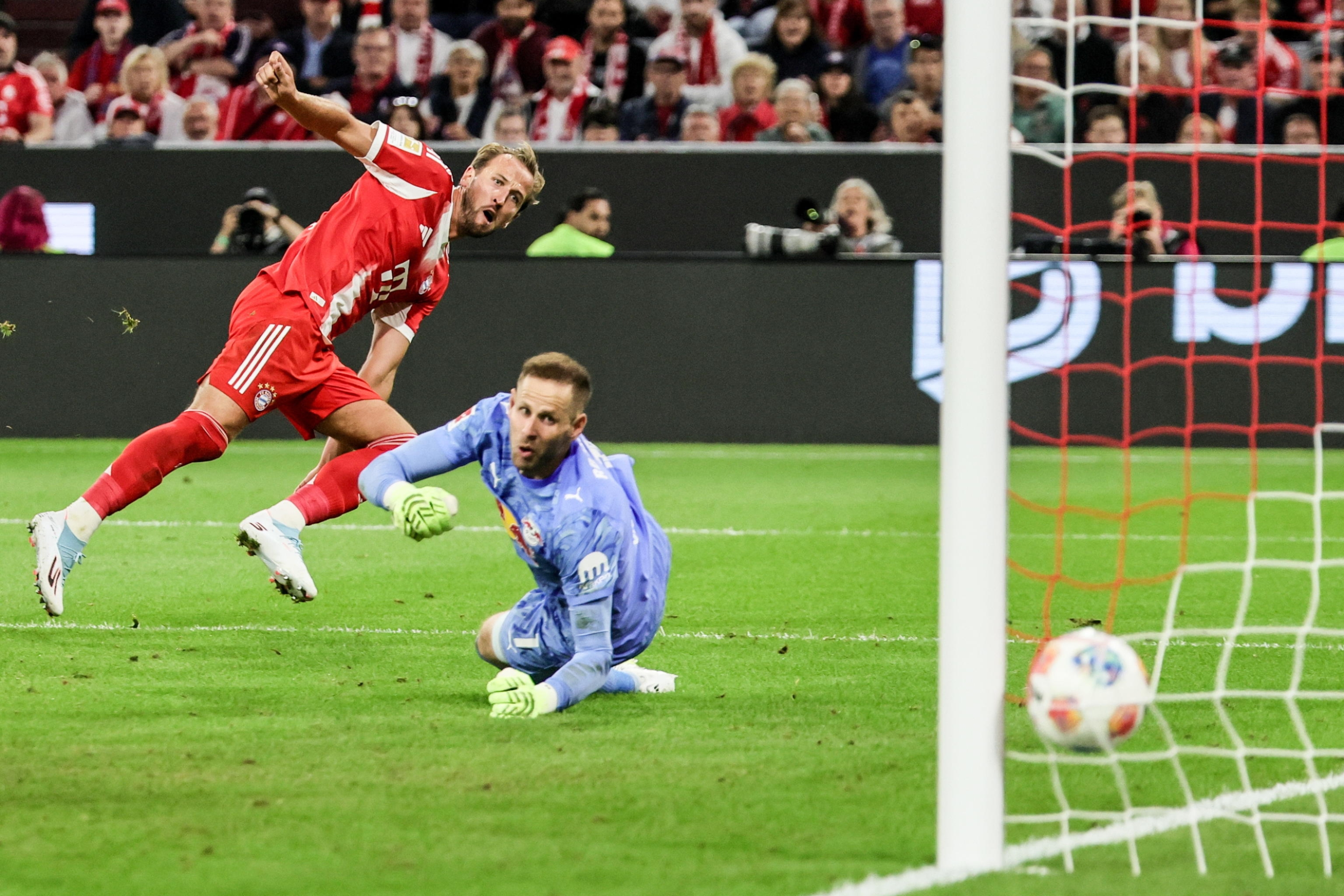 epa12317541 Harry Kane (L) of Munich scores against goalkeeper Peter Gulacsi of Leipzig during the German Bundesliga soccer match between FC Bayern Munich and RB Leipzig in Munich, Germany, 22 August 2025. EPA/RONALD WITTEK CONDITIONS - ATTENTION: The DFL regulations prohibit any use of photographs as image sequences and/or quasi-video.
