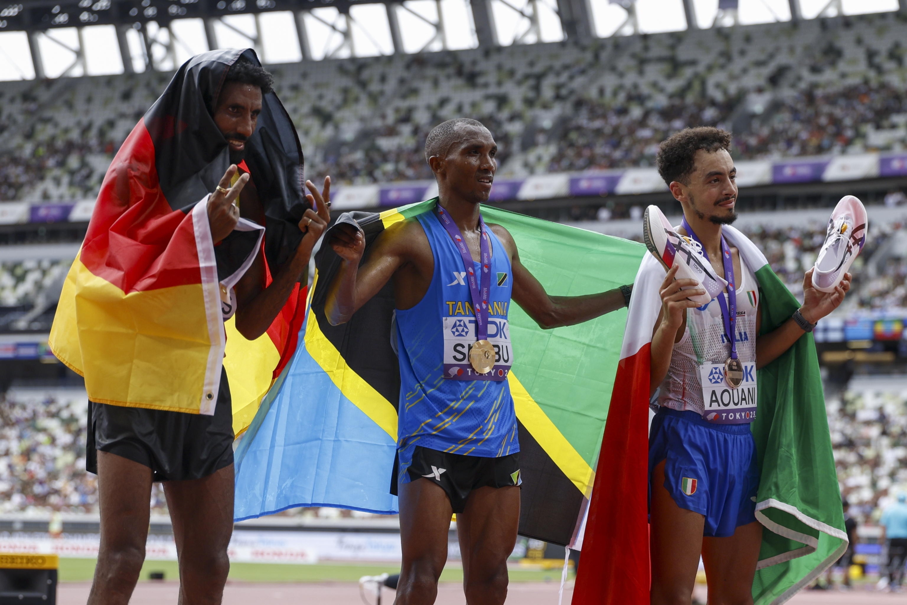 epa12378239 Gold medalist Alphonce Felix Simbu (C) of Tanzania, silver medalist Amanal Petros (L) of Germany and bronze medalist Iliass Aouani of Italy celebrate during the Men's Marathon at the World Athletics Championships 2025 in Tokyo, Japan, 15 September 2025. EPA/FRANCK ROBICHON