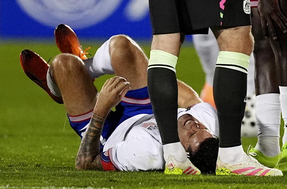 Christian Pulisic holding his leg in pain