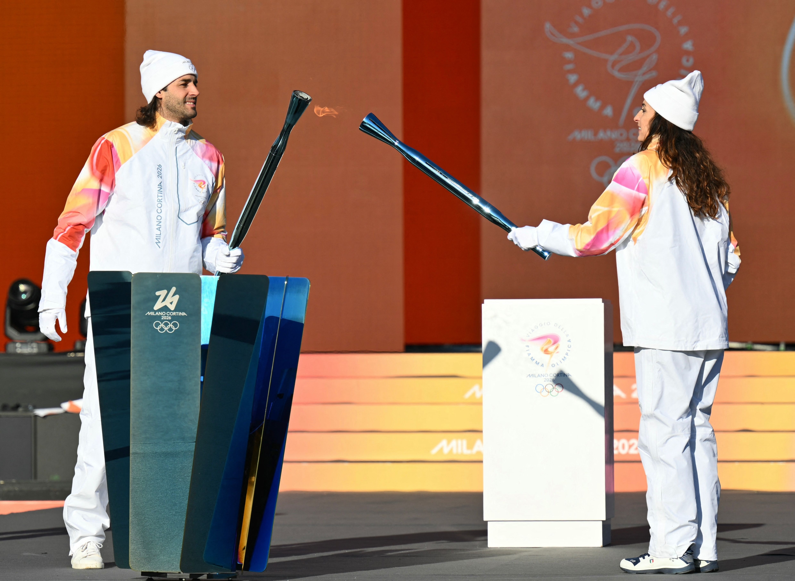Italy's high jump athlete and torchbearers Gianmarco Tamberi (L) and Italy's former fencing athlete Elisa Di Francisca lights the torch at the Stadio dei Marmi (Stadium of the Marbles) one of four stadiums located in the Foro Italico sports complex during the Torch Relay to Milano Cortina 2026 Olympic Games, in Rome on December 6, 2025. (Photo by Alberto PIZZOLI / AFP)